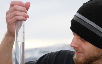 man looks at rain gauge to take measurements